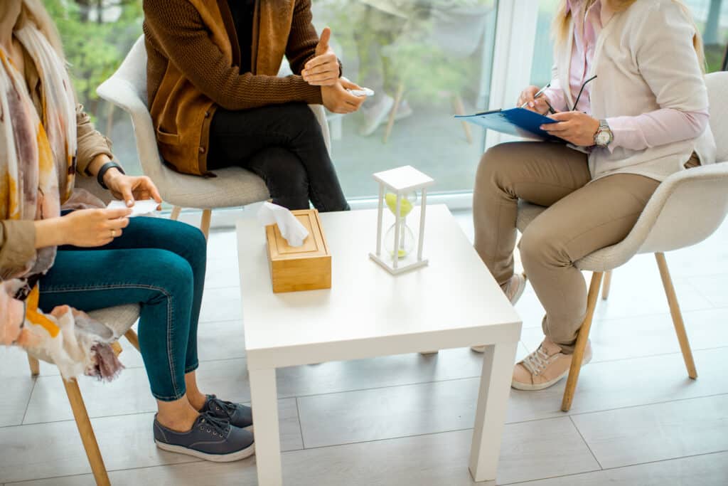 Couple sitting with psychologist during the mental therapy, cropped image with no face
